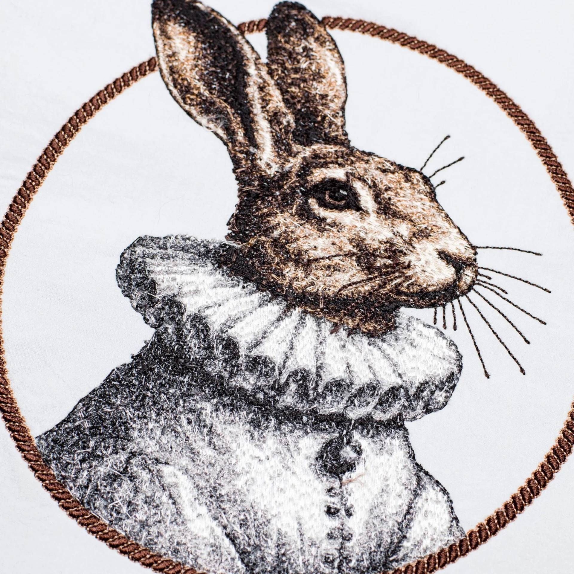 A close-up of a machine embroidery design featuring a rabbit in a ruffled collar, framed by an oval. The intricate threadwork showcases fine shading and texture, adding an elegant and vintage-inspired touch to embroidery projects.